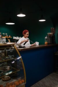 Barista tidying up the countertop in a cozy, dimly lit coffee shop.